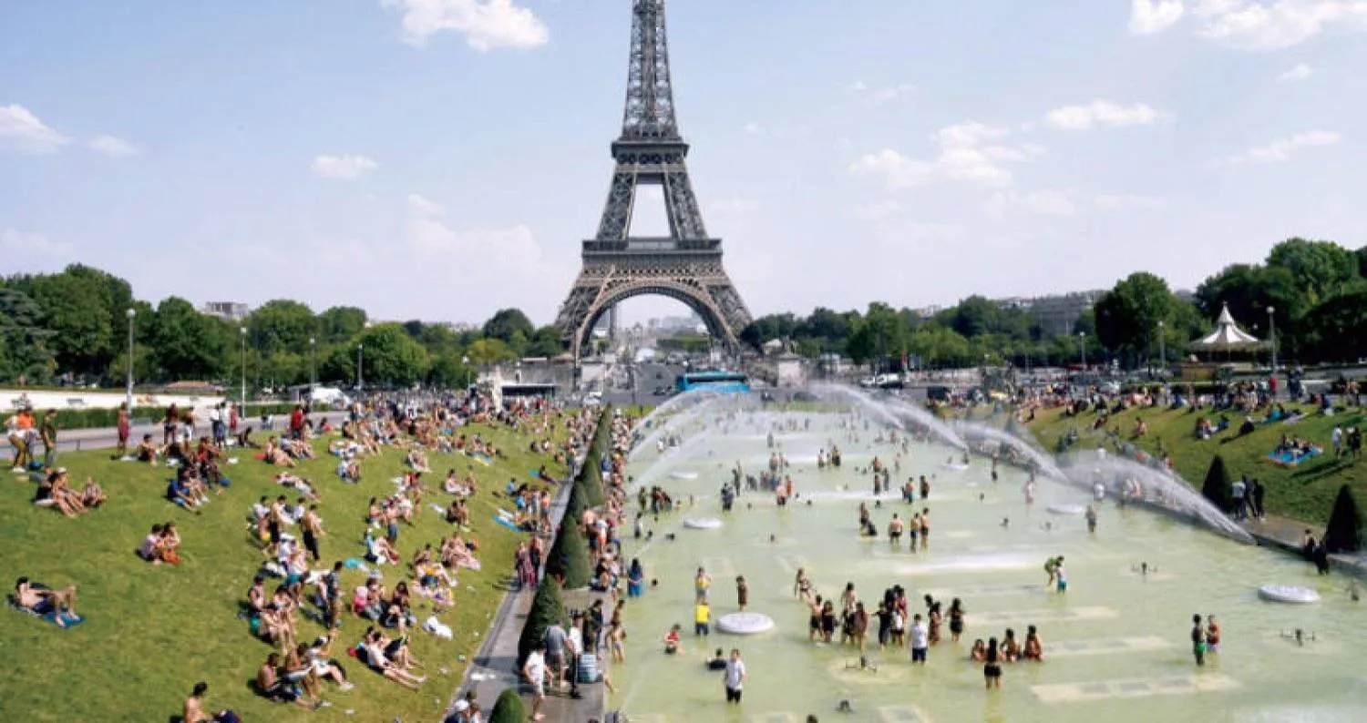 الحر دفع سكان باريس إلى اللجوء للنوافير والحدائق قرب برج إيفل (أ.ف.ب)