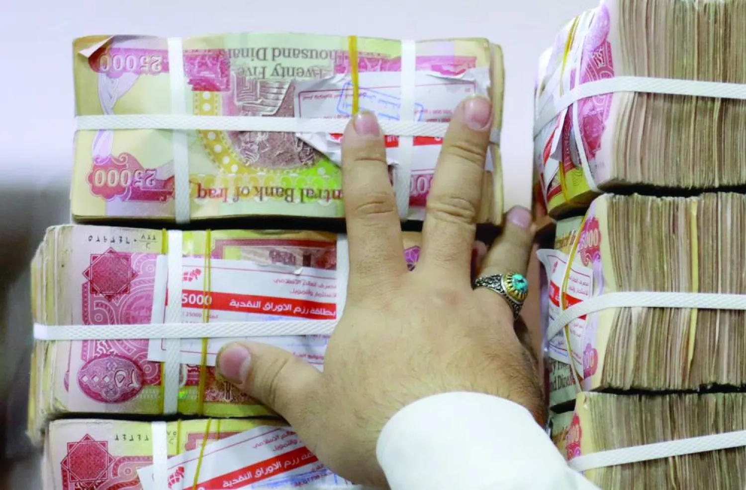موظف يرتب أكواماً من الدينار العراقي في محل صرافة ببغداد (أ.ف.ب)