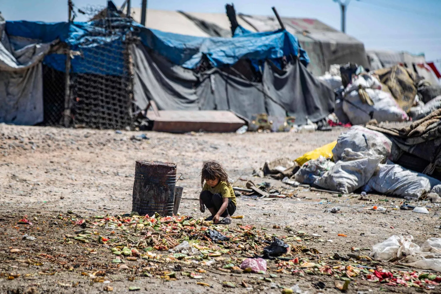 فتاة تغربل القمامة في مخيم سهلة البنات المؤقت للنازحين داخلياً الذي تم إنشاؤه بجوار مكب النفايات على مشارف مدينة الرقة شمال سوريا - 10 يوليو 2023 (أ.ف.ب)