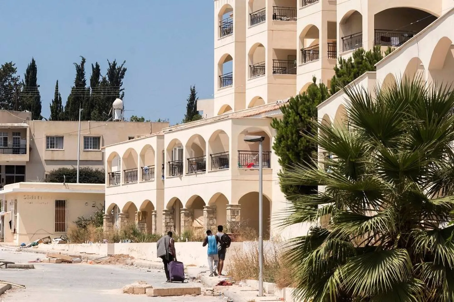 Asylum seekers transport belongings at the Ayios Nikolaos apartment complex, in Chloraka, a village of 7,000 people located on the outskirts of Paphos, on August 22, 2023. (AFP) 