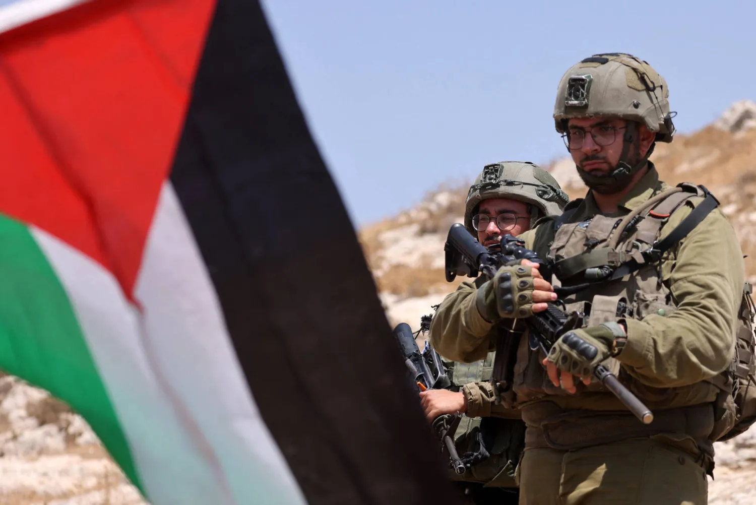 جنود إسرائيليون يقفون خلف العلم الفلسطيني في نابلس (أ.ف.ب)