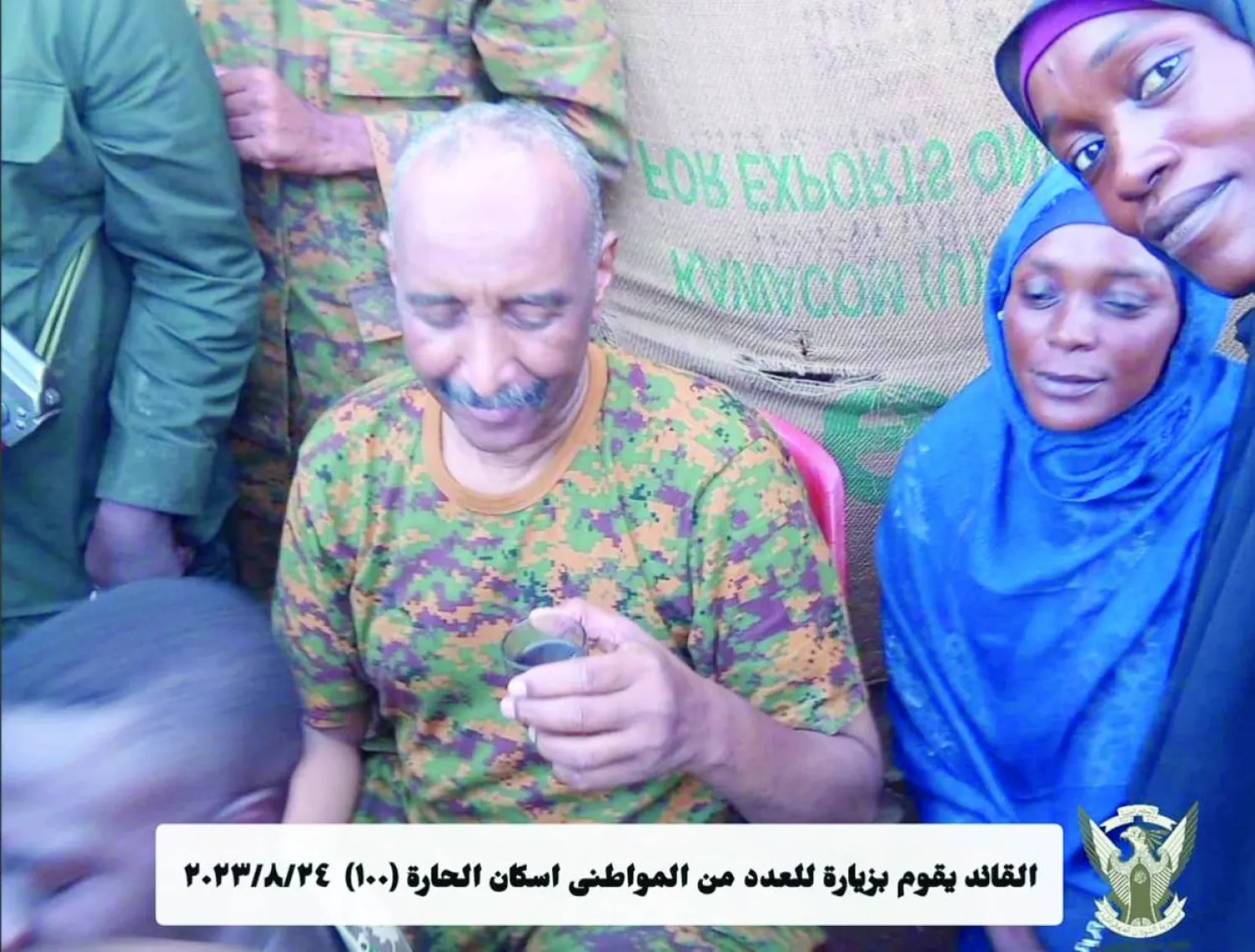 البرهان يتناول كوباً من الشاي مع إحدى البائعات في أحد محلات أمدرمان (موقع الجيش على «فيسبوك»)