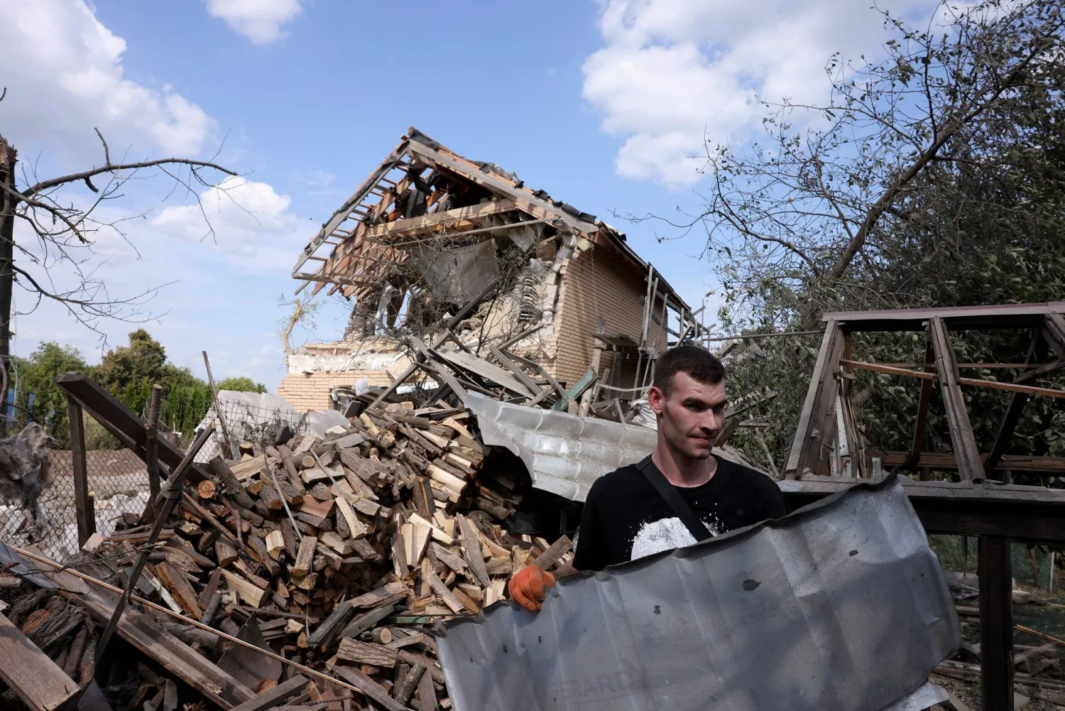 أوكراني يزيل الركام في قرية روليكيف قرب العاصمة كييف الأحد بعد هجوم صاروخي روسي (إ.ب.أ)