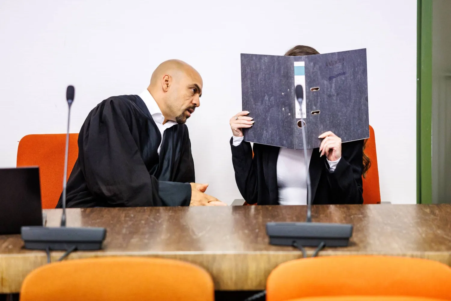 المتهمة (على اليمين) التي يُزعم أنها انضمت إلى ميليشيا تنظيم (داعش) في العراق تحمل ملفاً أمام وجهها بجوار محاميها طارق العبيد في قاعة المحكمة الإقليمية العليا في ميونخ حيث تواجه المرأة البالغة من العمر 32 عاماً السجن 14 عاماً لقتلها فتاة إيزيدية (د.ب.أ)