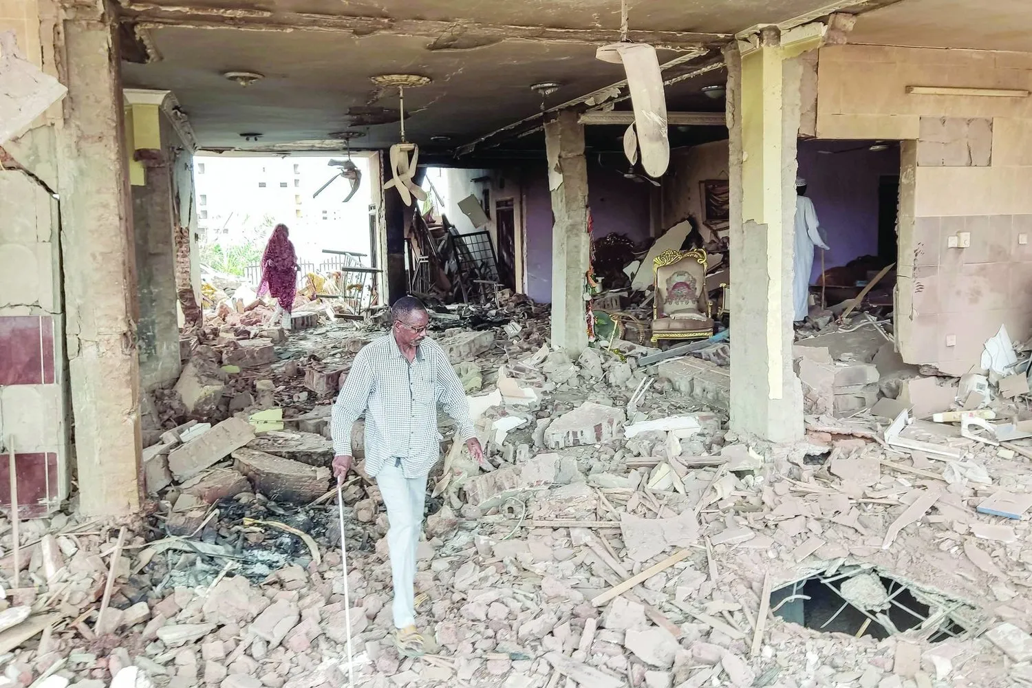 Sudanlı bir vatandaş, Hartum'un güneyinde kalan el-Ezheri mahallesinde yıkılan bir evin enkazını inceliyor. (AFP)