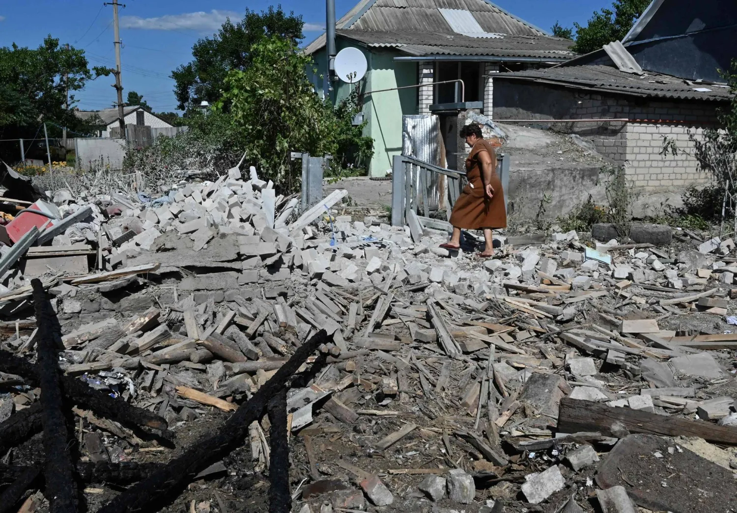 سيدة أوكرانية تسير وسط دمار أحد المنازل في مدينة كوبيانسك بشرق أوكرانيا (أ.ف.ب)