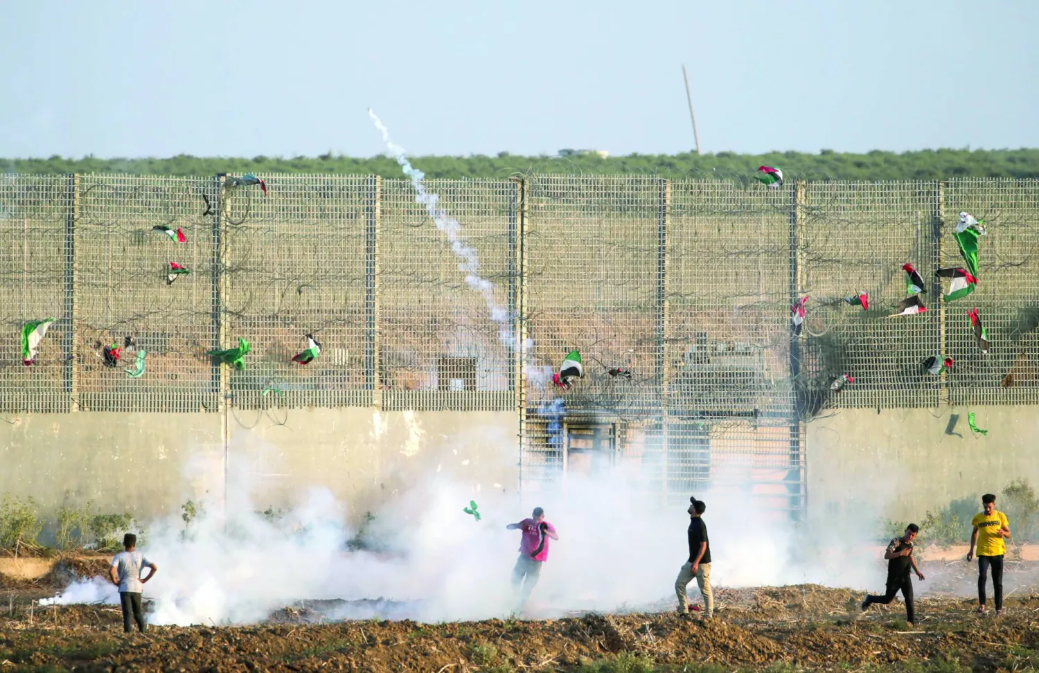 فلسطينيون خلال احتجاجات أمام السياج الفاصل بين شرق قطاع غزة والأراضي الإسرائيلية يوم الجمعة (إ.ب.أ)