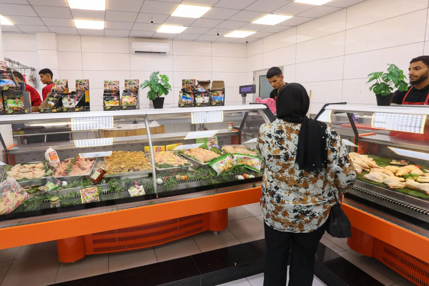 سيدة تنتظر طلبها من جزار (قصاب) في طرابلس الليبية (أ.ف.ب)