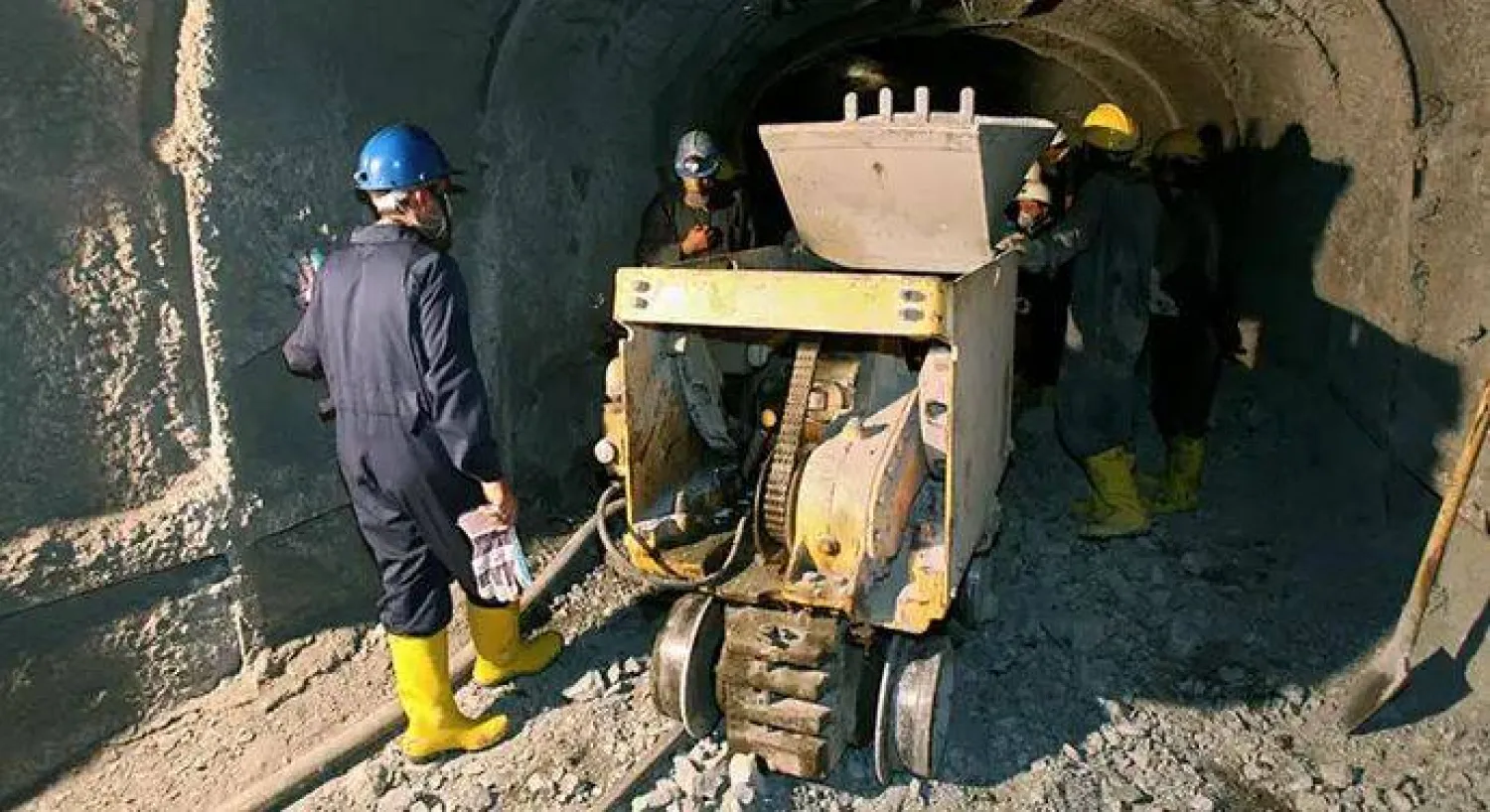 عمال إيرانيون يقفون حول معداتهم عند مدخل منجم وسط البلاد (أرشيفية - د.ب.أ)