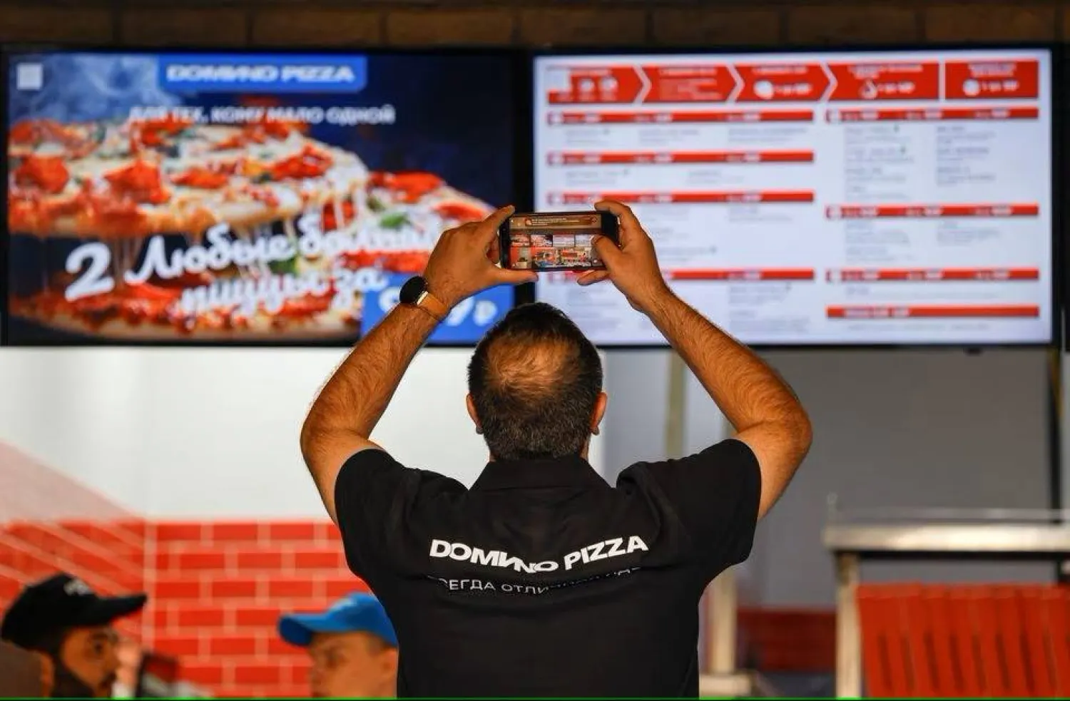 عامل يلتقط صورة تذكارية خلال افتتاح سلسلة «دومينو بيتزا» في العاصمة الروسية موسكو والتي قامت بالاستحواذ على ممتلكات «دومينوز بيتزا» عقب مغادرة الأخيرة روسيا (رويترز)