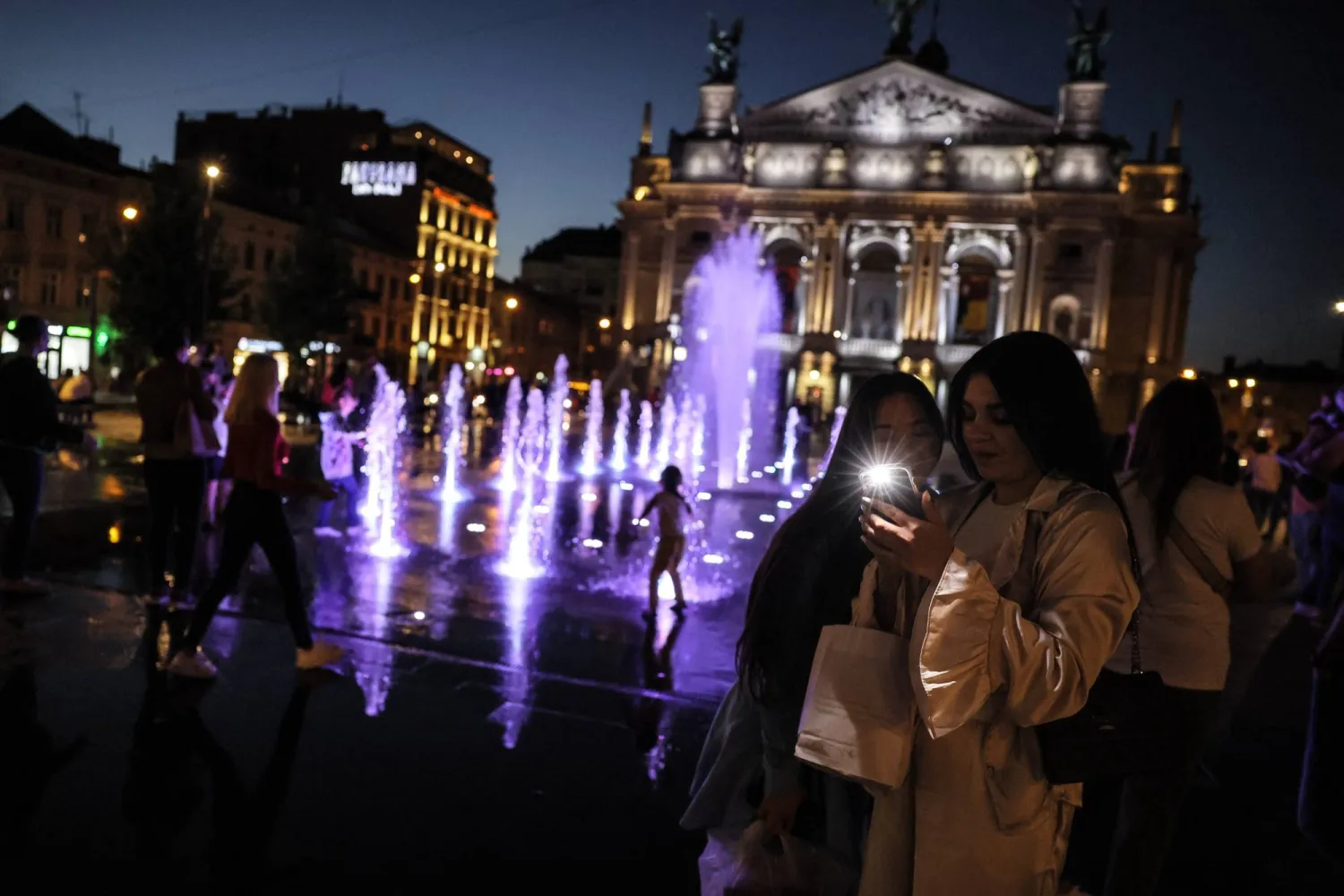 مواطنون بالقرب من مسرح الأوبرا في مدينة لفيف الأوكرانية (إ.ب.أ)