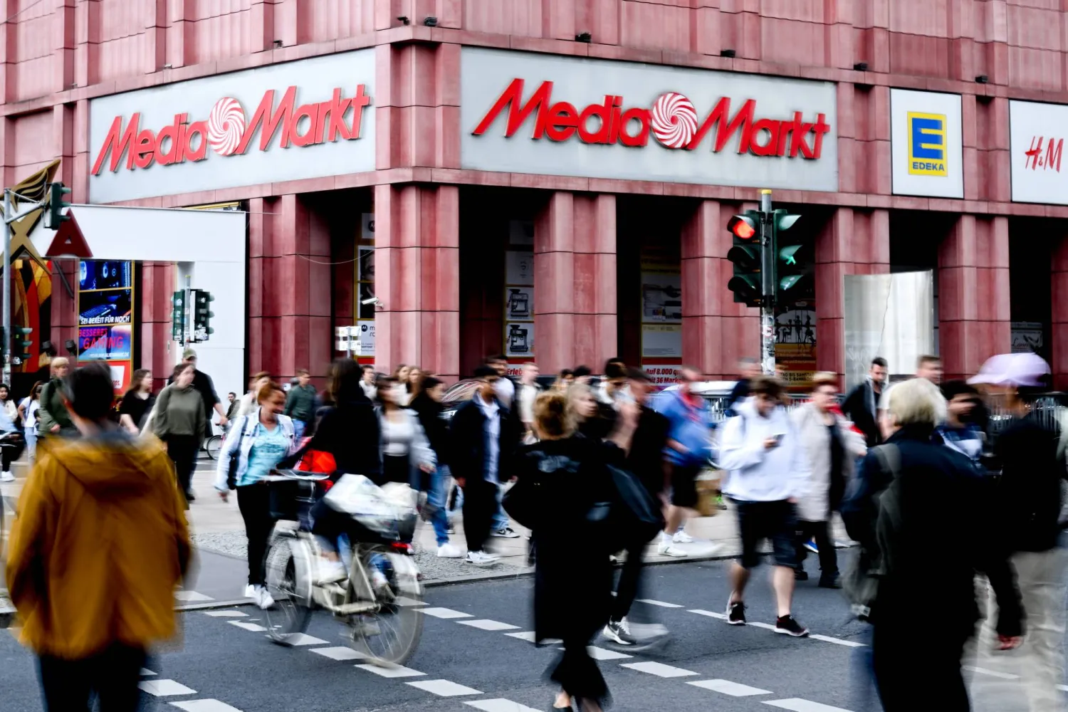 مشاة يسيرون في منطقة تسوق بالقرب من ميدان ألكسندر في برلين بألمانيا (إ.ب.أ)