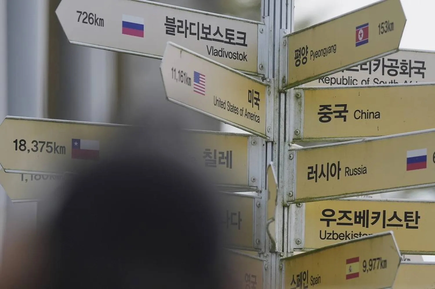 A visitor takes a photo in front of destination signs including North Korea's capital Pyongyang and Russia's city Vladivostok at the Imjingak Pavilion in Paju, South Korea, Tuesday, Sept. 12, 2023. (AP)