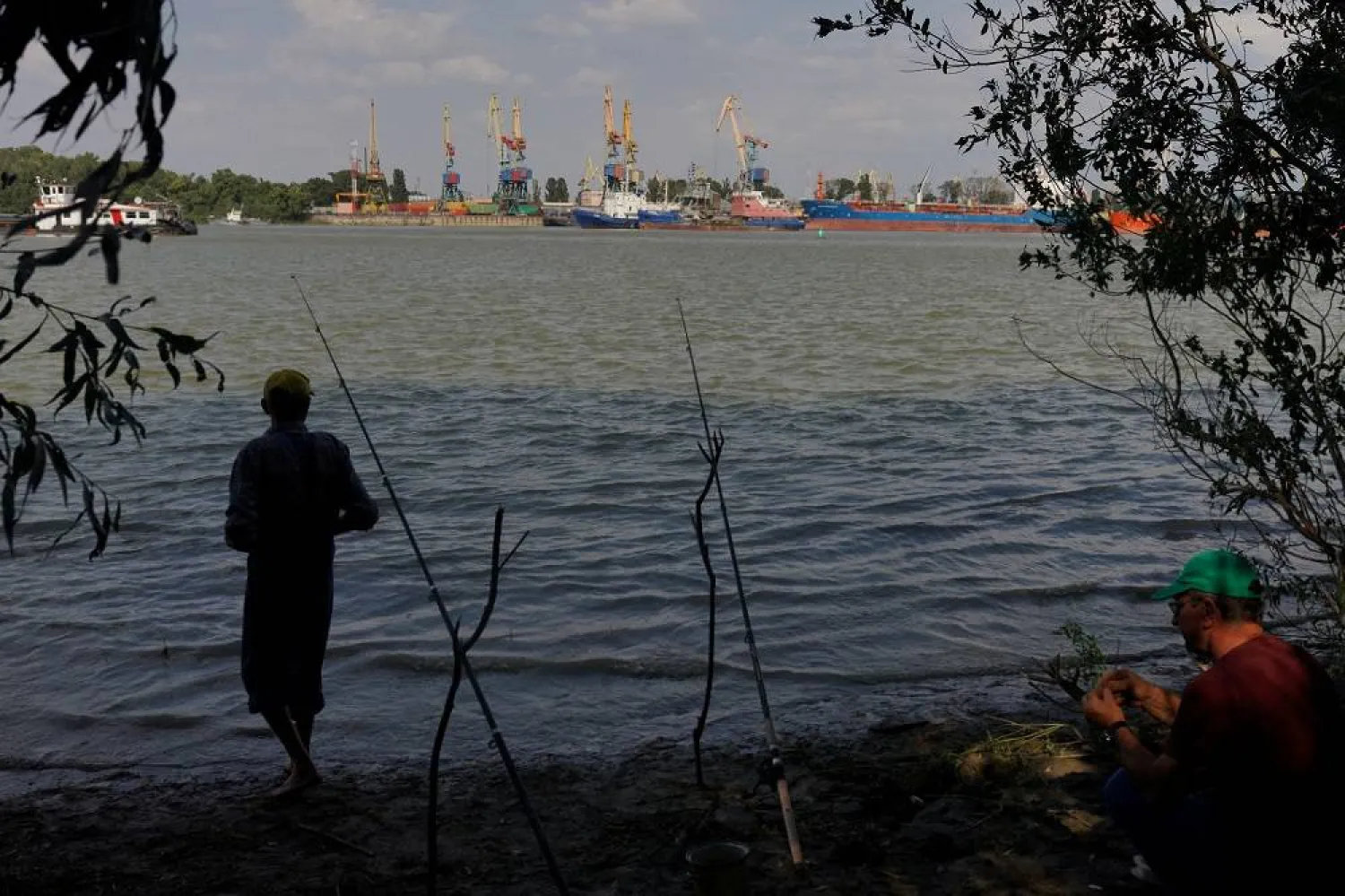 Two men prepare to fish across the Danube from the port of Izmail, in Plauru, Romania, September 5, 2023. (Reuters)