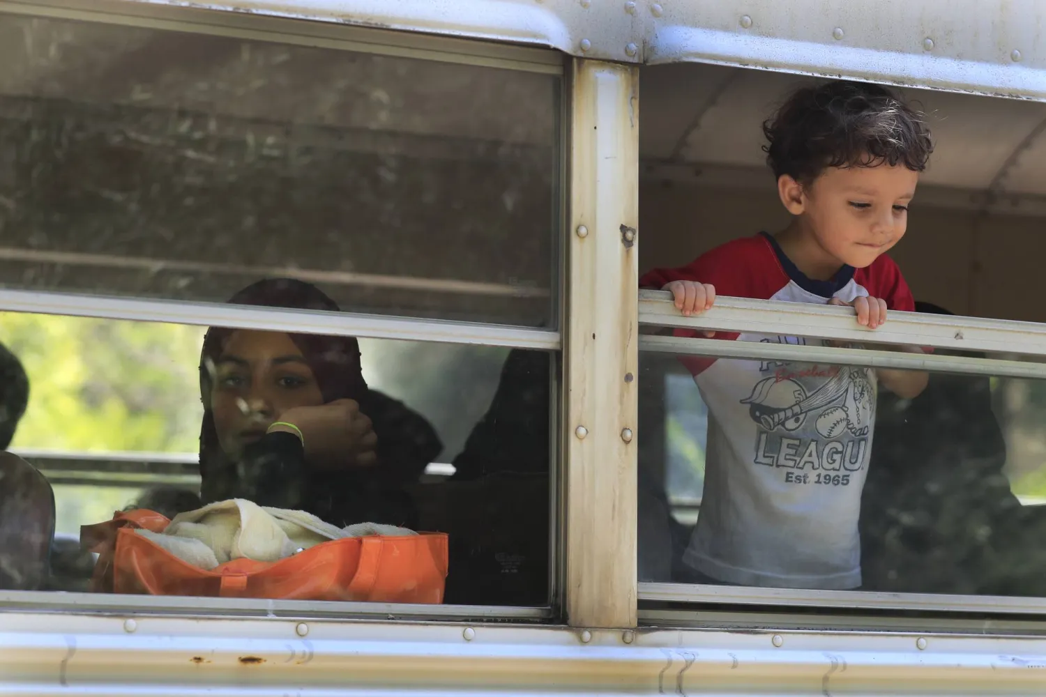 فلسطينية وطفلها في حافلة تنقلهما إلى مدرسة لـ«الأونروا» خصصت لإيواء الفارين من معارك «عين الحلوة» (أ.ب)