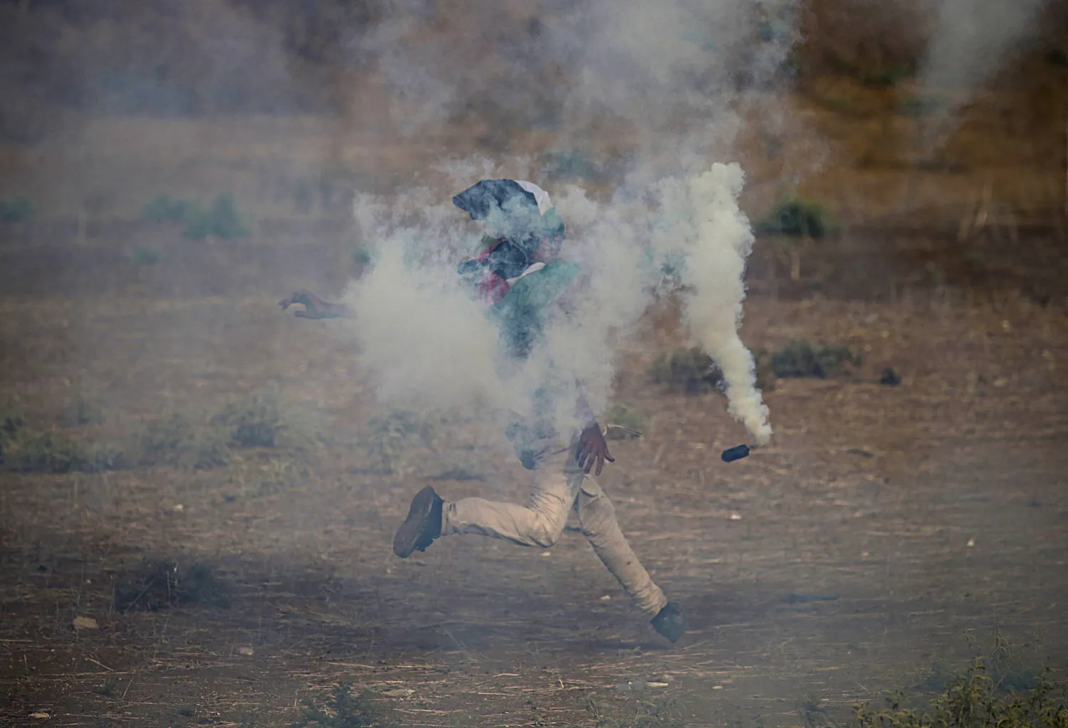 متظاهر فلسطيني يعيد رمي قنبلة غاز مسيل للدموع خلال اشتباكات مع القوات الإسرائيلية على الحدود الشرقية لقطاع غزة اليوم (إ.ب.أ)