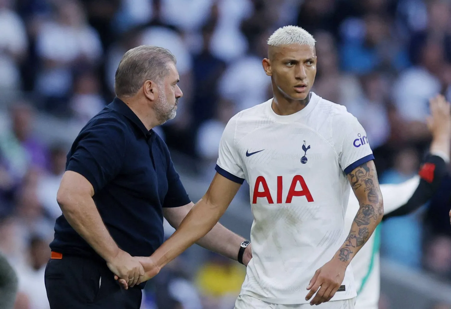 البرازيلي ريتشارليسون مصافحاً مدربه أنغي بوستيكغلو خلال إحدى منافسات الدوري الإنجليزي (رويترز)