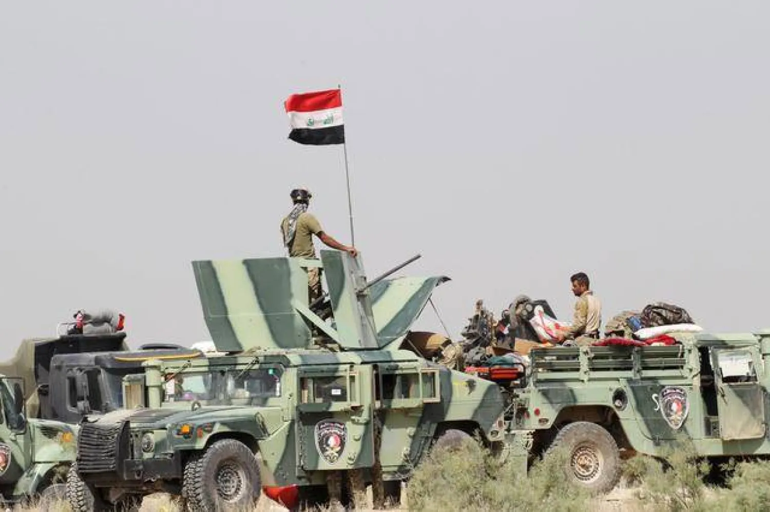 عناصر من القوات العراقية تجلس في آليات عسكرية (رويترز)