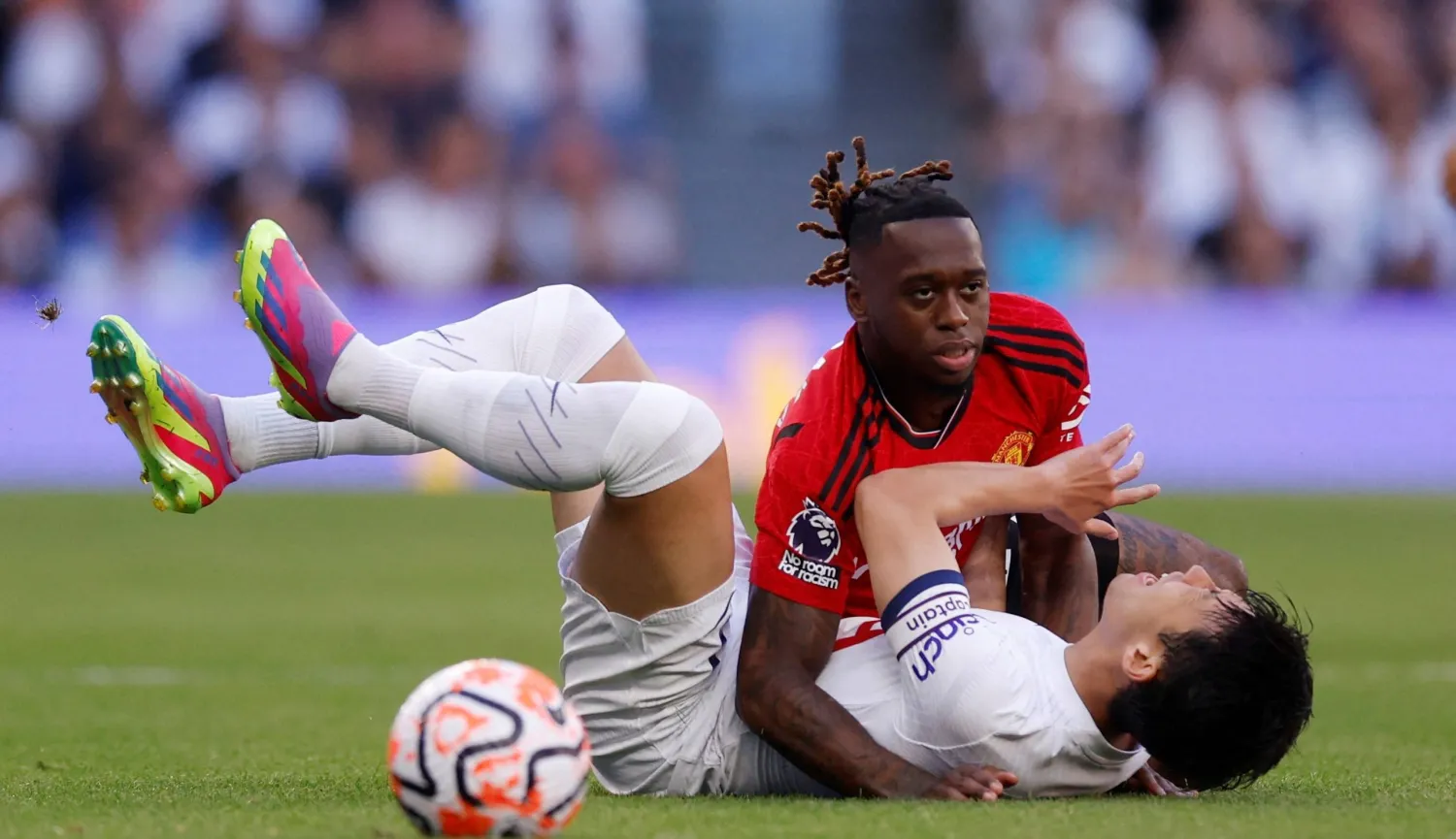 وان بيساكا مدافع مان يونايتد خلال ارتكابه خطأً على سون هيونغ لاعب توتنهام بالمواجهة التي جمعت الفريقين (رويترز)