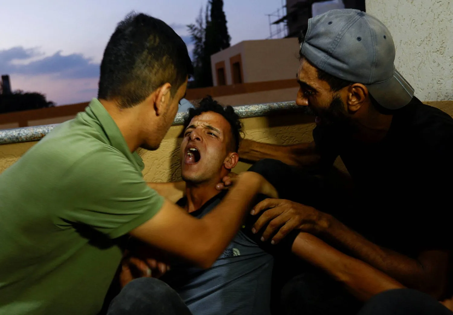 أقرباء الشاب يوسف رضوان يبكون بعد مقتله قرب السياج الفاصل بين قطاع غزة وإسرائيل (رويترز)