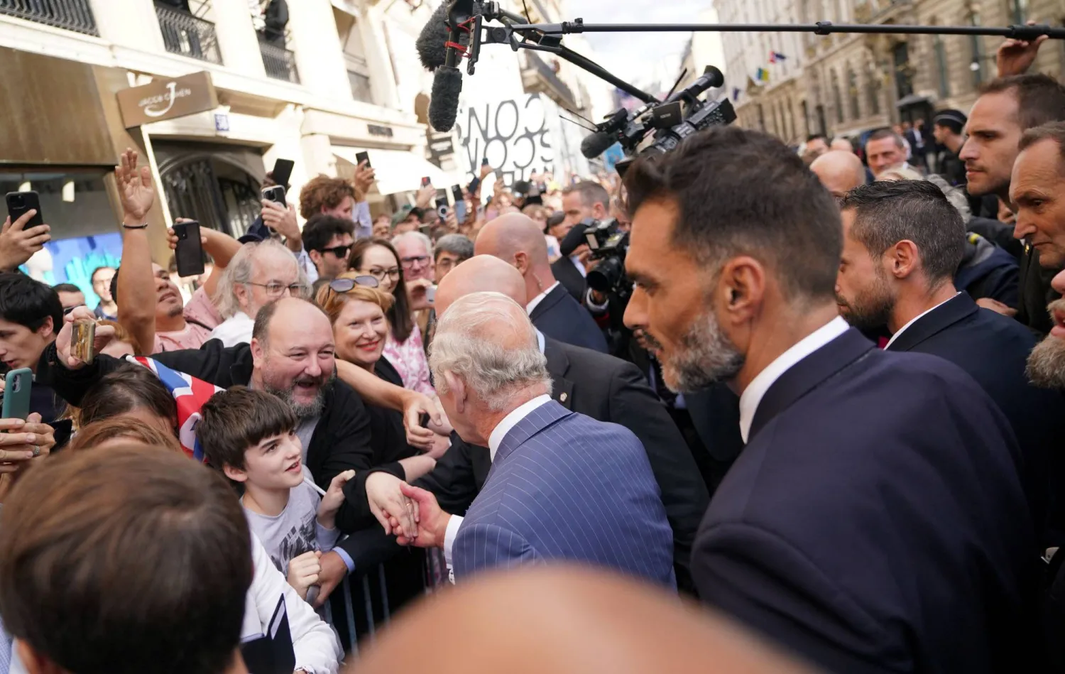 الملك تشارلز خلال مصافحته المواطنين في جادة الشانزليزيه (رويترز)