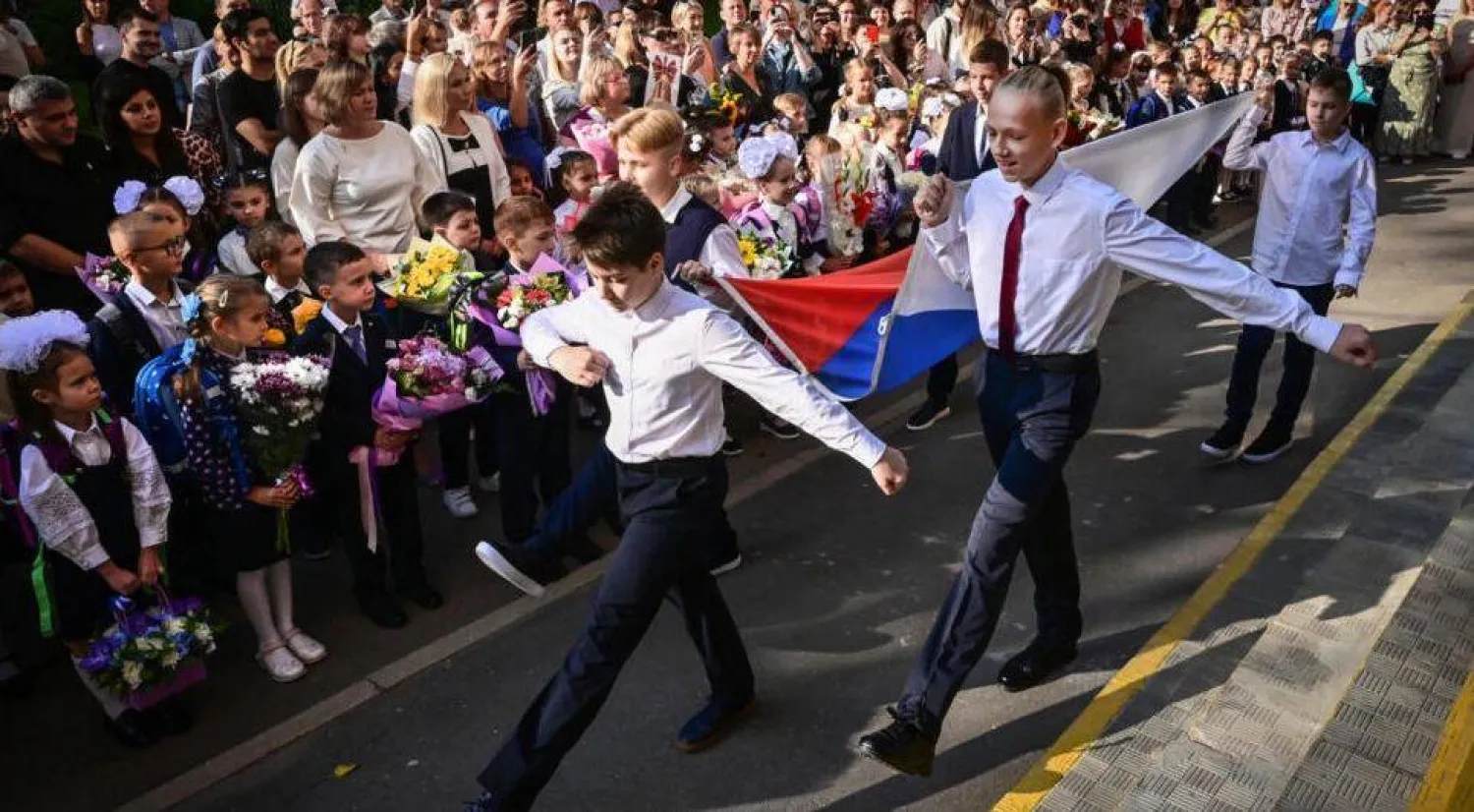 طلاب يحملون علم روسيا في إحدى المدارس (أ.ف.ب)