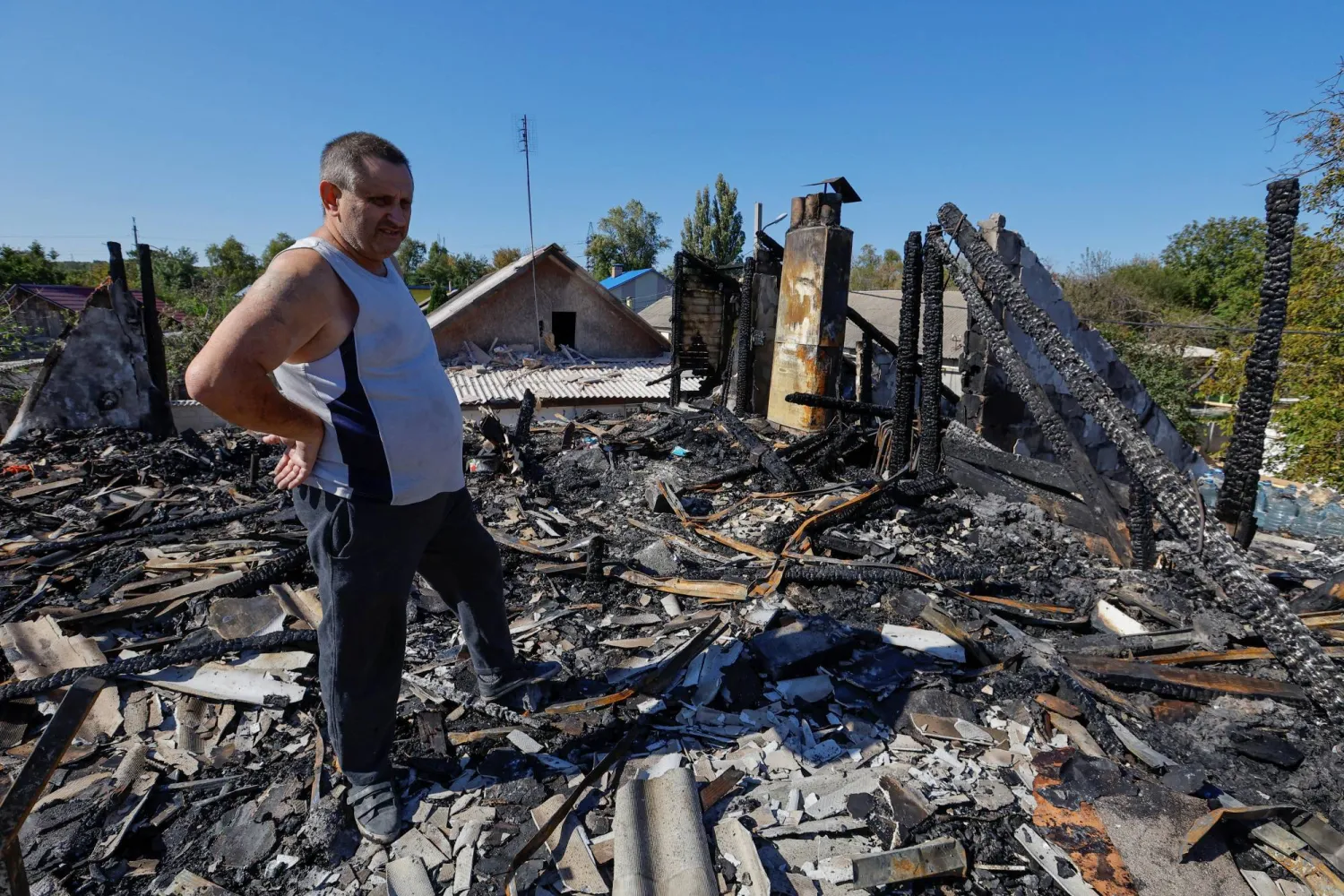 رجل يقف أمام منزله المُدمر بفعل القصف في إحدى بلدات دونيتسك الأحد (رويترز)