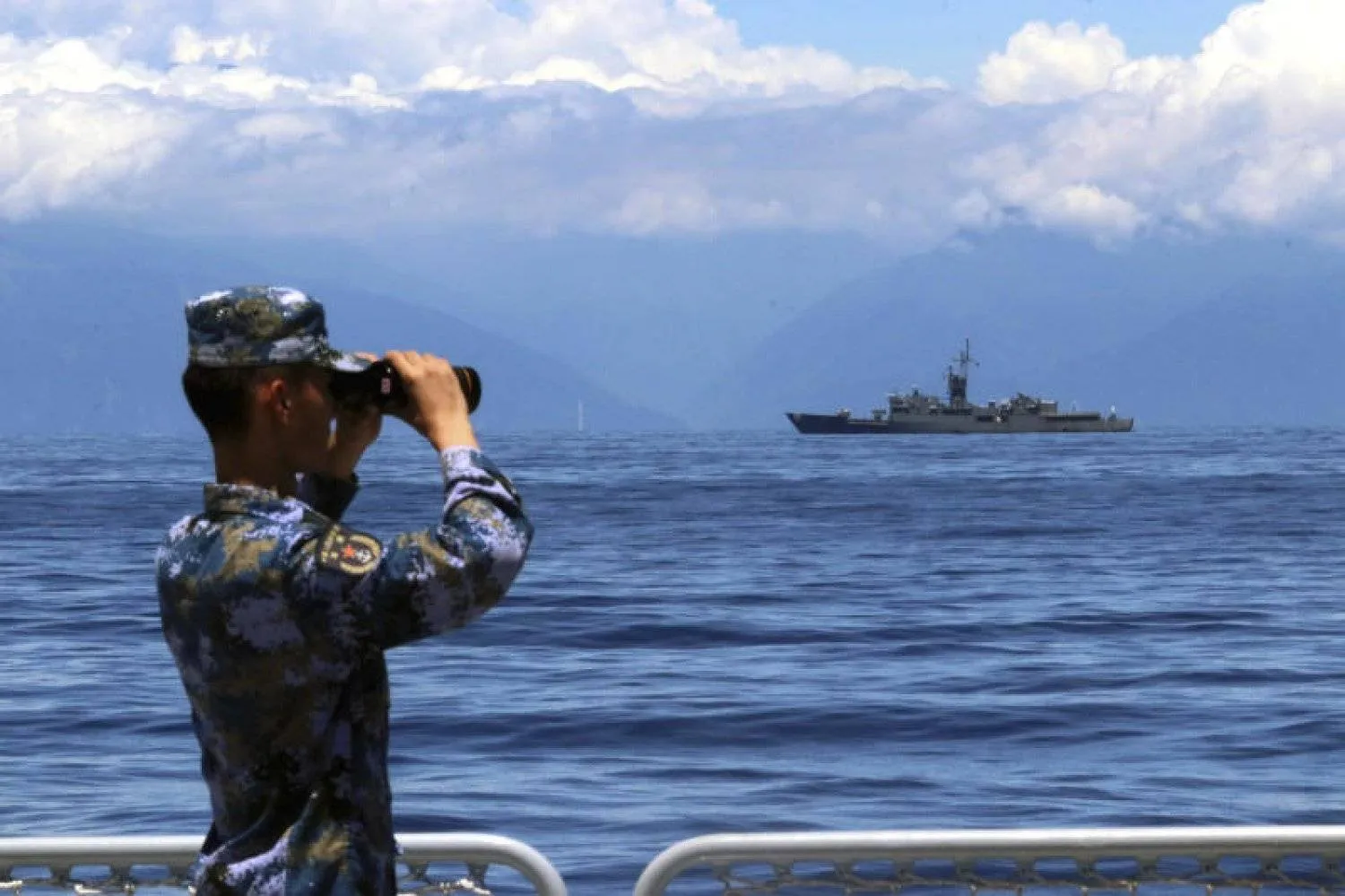 In this photo provided by China’s Xinhua News Agency, a People's Liberation Army member looks through binoculars during military exercises as Taiwan’s frigate Lan Yang is seen at the rear, on Friday, August 5, 2022. Lin Jian, AP