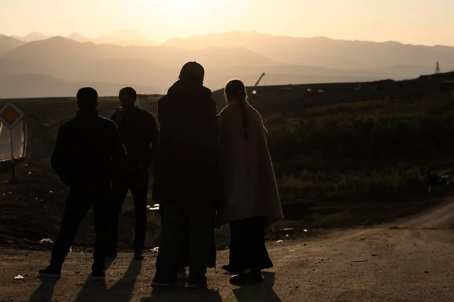 Refugees stand near the road with the Karabakh mountains in the background after crossing the border near Kornidzor on September 28, 2023. (AFP)