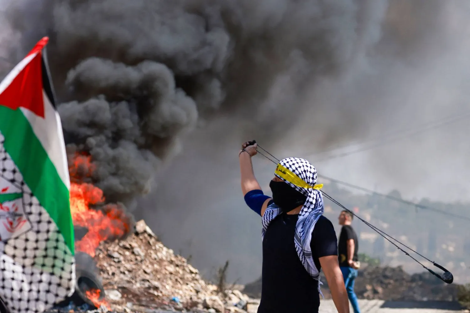 A protester hurls stones at members of the Israeli forces as they clash in the village of Kfar Qaddum, in the occupied West Bank, on September 29, 2023, during a demonstration against expropriation of Palestinian land by Israel. (Photo by Jaafar ASHTIYEH / AFP)