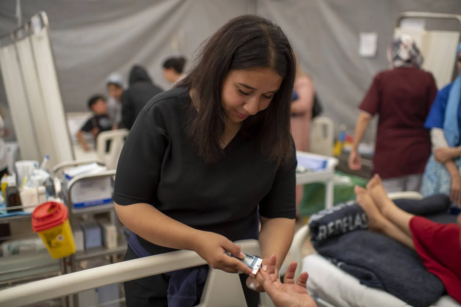 طبيبة تقدم الإسعافات لمصابة في منطقة أمزميز التي ضربها الزلزال (إ.ب.أ)