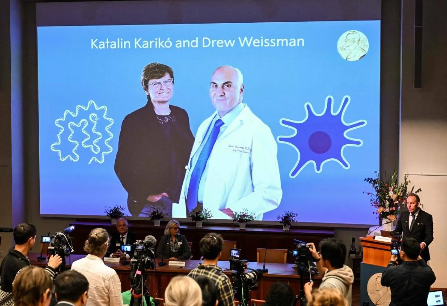 A screen at the Karolinska Institute shows this year's laureates Katalin Kariko of Hungary (L) and Drew Weissman of the US during the announcement of the winners of the 2023 Nobel Prize in Physiology or Medicine at the Karolinska Institute in Stockholm on October 2, 2023. (AFP)