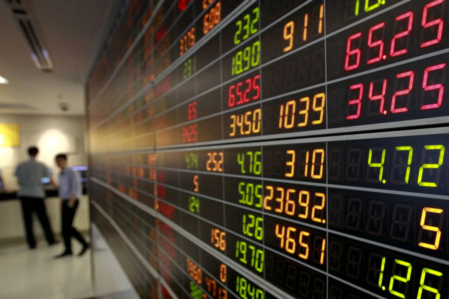 متداولون يتابعون حركة الأسهم على شاشة عملاقة في العاصمة التايلاندية بانكوك (رويترز)