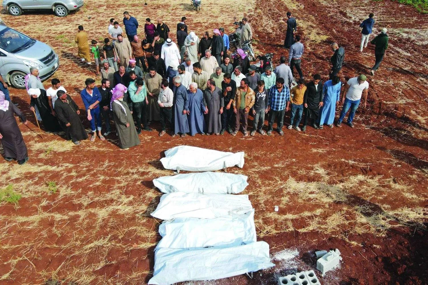 سوريون يصلون على امرأة و4 من أطفالها قتلوا بقصف لدمشق على كفر نوران في محافظة حلب عقب استهداف «مسيرات» للكلية الحربية في حمص (أ.ف.ب)