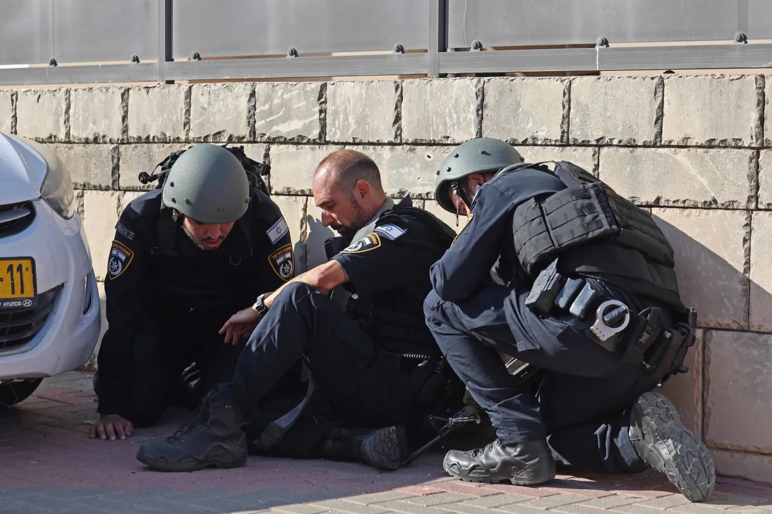 عناصر من القوات الإسرائيلية يحتمون على جانب أحد الشوارع في عسقلان بينما تنطلق صفارات الإنذار بينما يتم إطلاق وابل من الصواريخ من قطاع غزة على إسرائيل (أ.ف.ب)