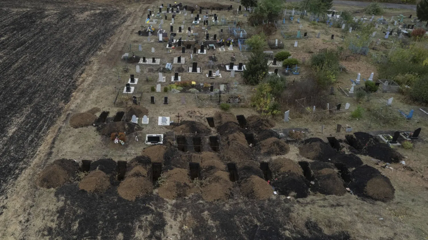 منظر جوي يُظهر قبوراً فارغة أُعدت لدفن أشخاص قُتلوا الخميس بهجوم صاروخي روسي في بلدة هروزا قرب خاركيف (أ.ب)