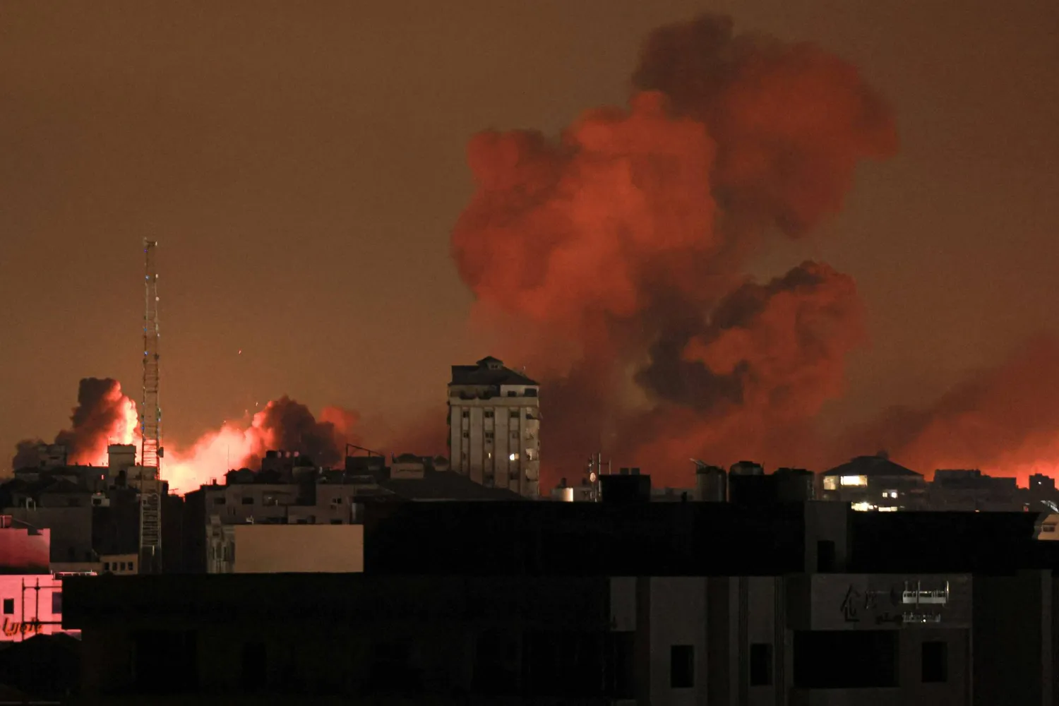 A plume of smoke rises above buildings in Gaza City during an Israeli airstrike, on October 8, 2023. (Photo by MAHMUD HAMS / AFP)