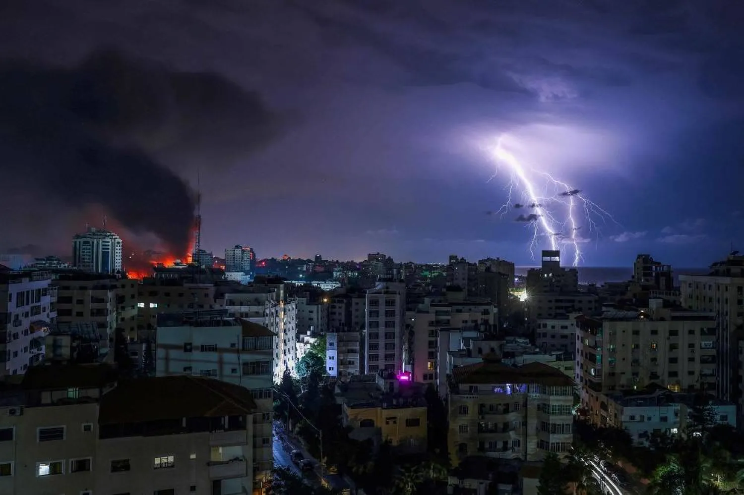 Lightning strikes as smoke billows following an Israeli airstrike in Gaza City on October 9, 2023. (AFP)