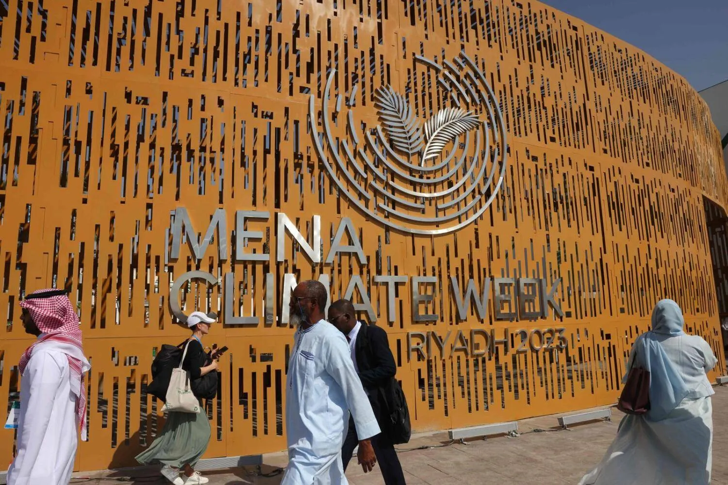 People walk past the entrance of the convention center before the opening session of the Middle East and North Africa (Mena) Climate Week, a UN-organised conference hosted in the Saudi capital Riyadh, on October 8, 2023. — AFP