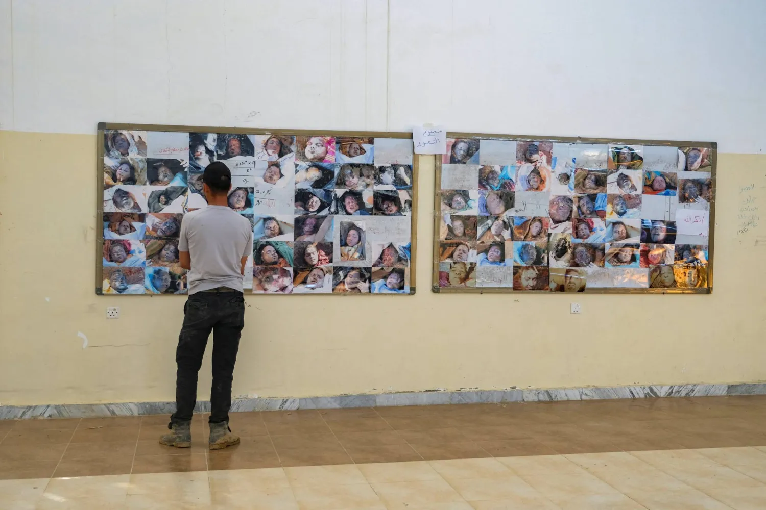 أحد سكان درنة يبحث عن صورتَي والده وأخيه المختفيين ضمن صور ضحايا الإعصار (رويترز)