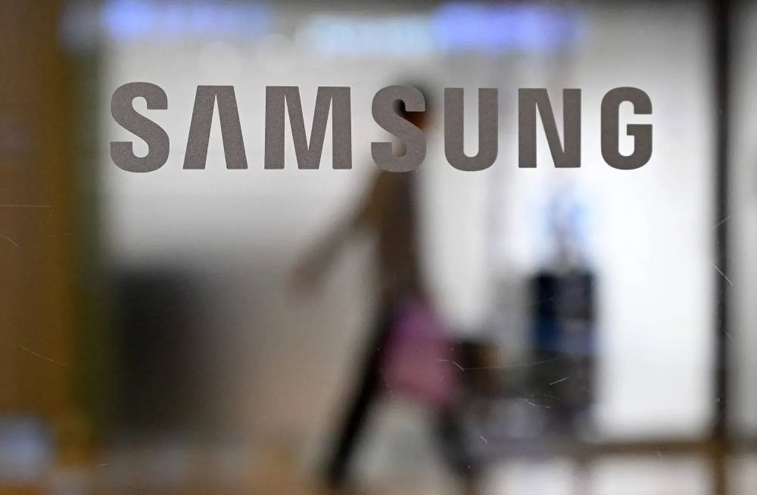 A man walks past the Samsung logo displayed on a glass door at the company's Seocho building in Seoul on October 11, 2023. (AFP)