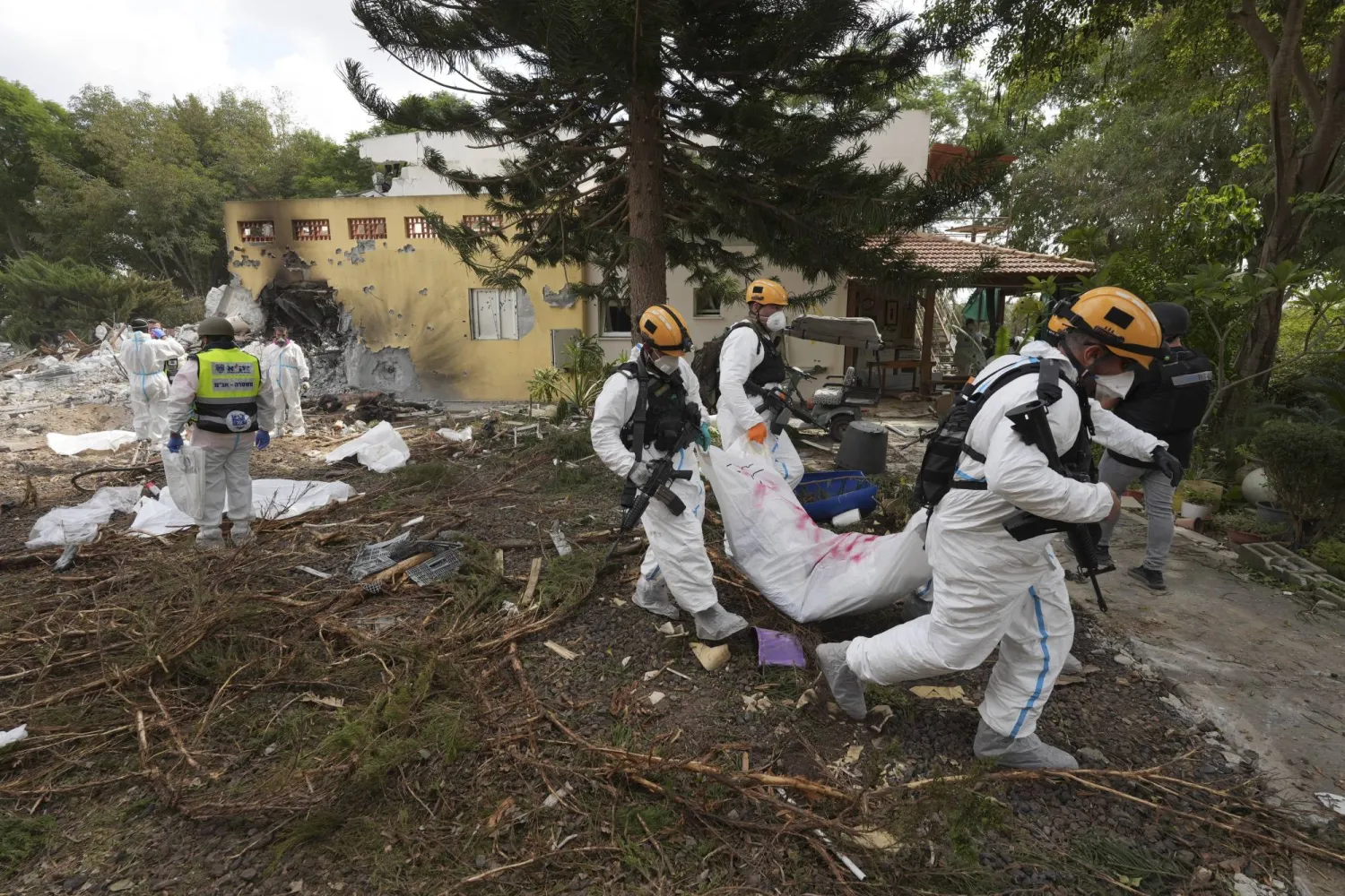 جنود إسرائيليون يحملون جثة مقاتل من «حماس» في كيبوتس بيري في غلاف غزة اليوم (أ.ب)