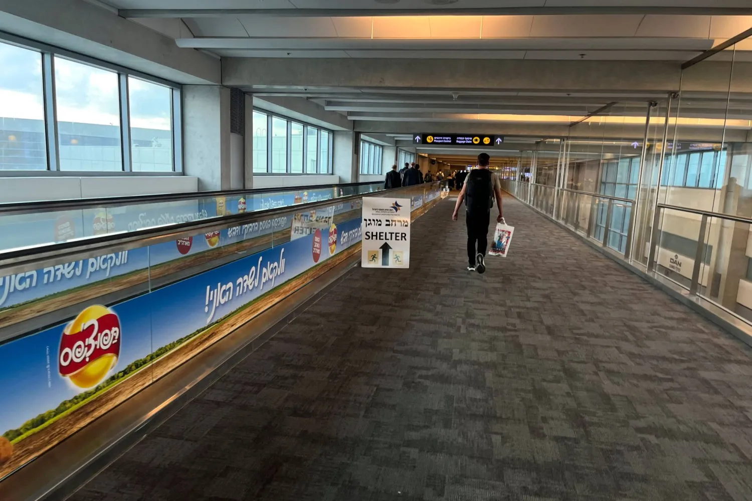 A sign informing passengers about the location of rocket shelters is set-up in a hallway as travelers arrive at Ben Gurion International Airport near Tel Aviv on October 10, 2023. (Photo by Yuri CORTEZ / AFP)