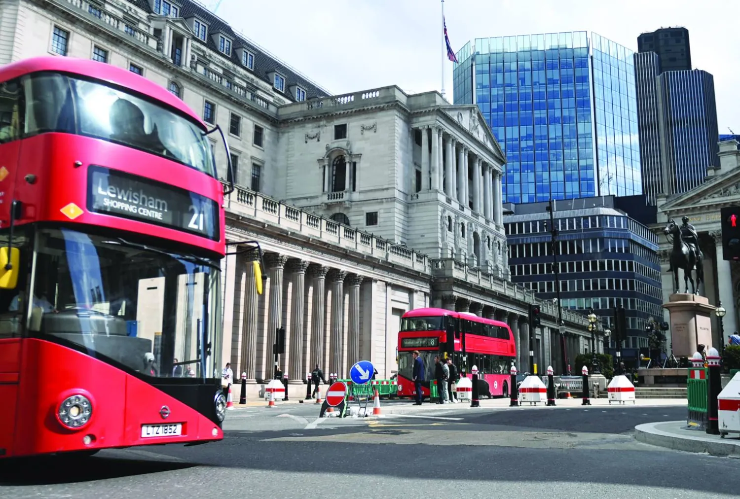 حافلات تمر بجوار بنك إنجلترا (المركزي البريطاني) في حي المال بمدينة لندن ببريطانيا (إ.ب.أ)