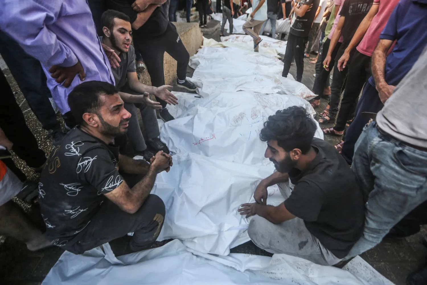 فلسطينيون يبكون فوق جثث ضحايا القصف الإسرائيلي على غزة خارج مشرحة مستشفى الشفاء في غزة (د.ب.أ)