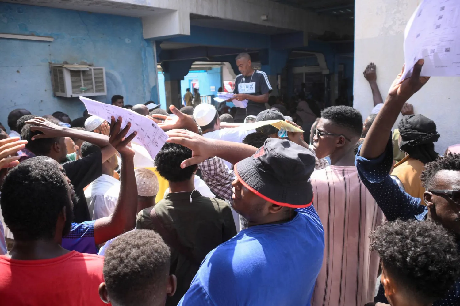 سودانيون يتجمعون أمام مركز رسمي للوثائق في بورتسودان انتظاراً للحصول على جوازات السفر (رويترز)