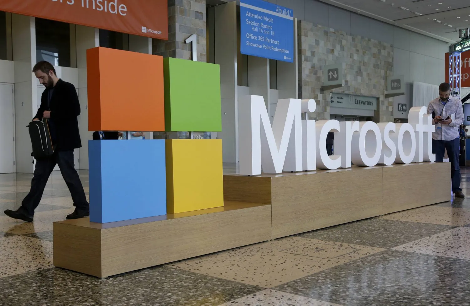 FILE - A man walks past a Microsoft sign set up for the Microsoft BUILD conference, April 28, 2015, at Moscone Center in San Francisco. (AP Photo/Jeff Chiu, File)