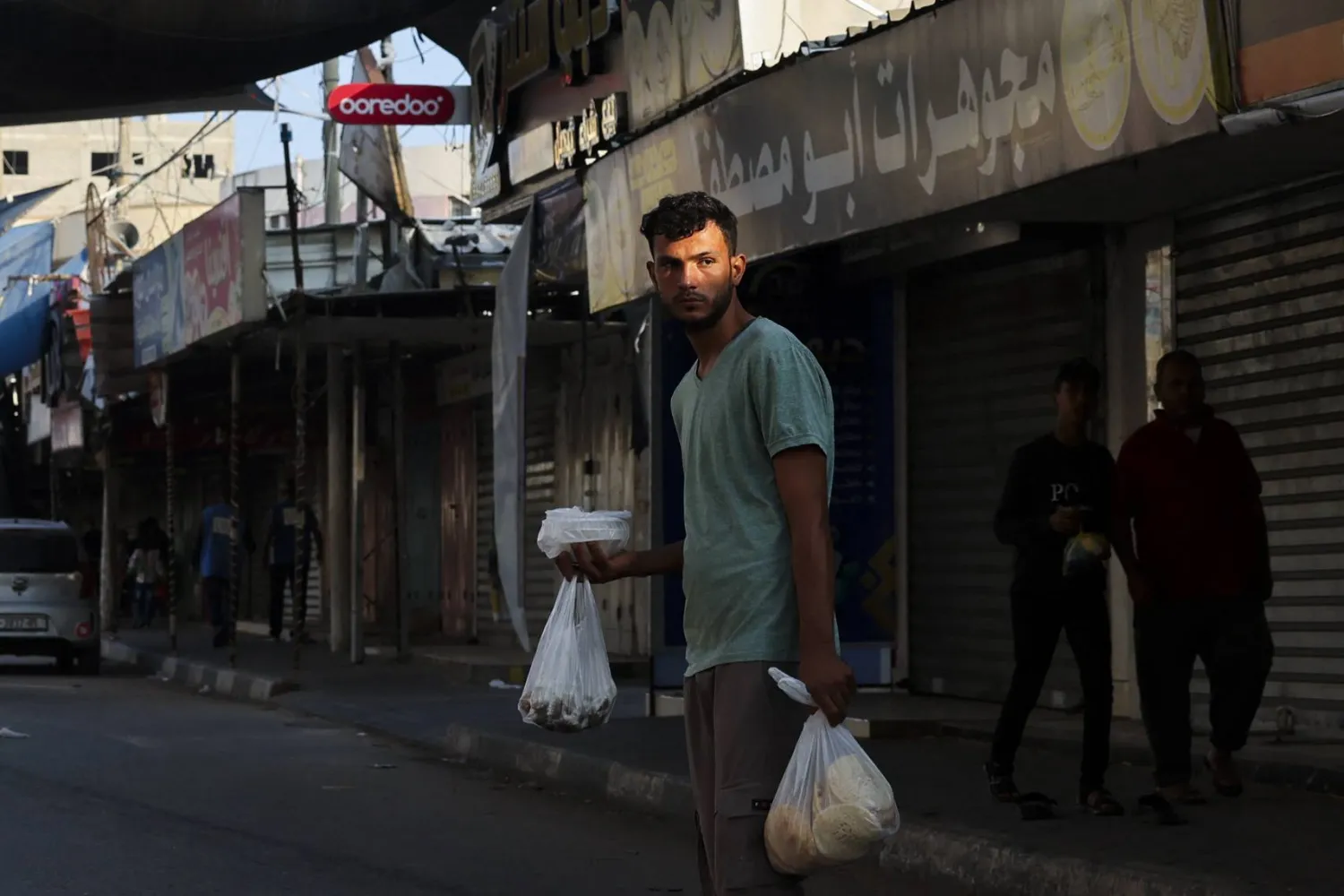 فلسطيني يعبر الشارع بعد الحصول على غذاء في خان يونس جنوب قطاع غزة (أ.ف.ب)