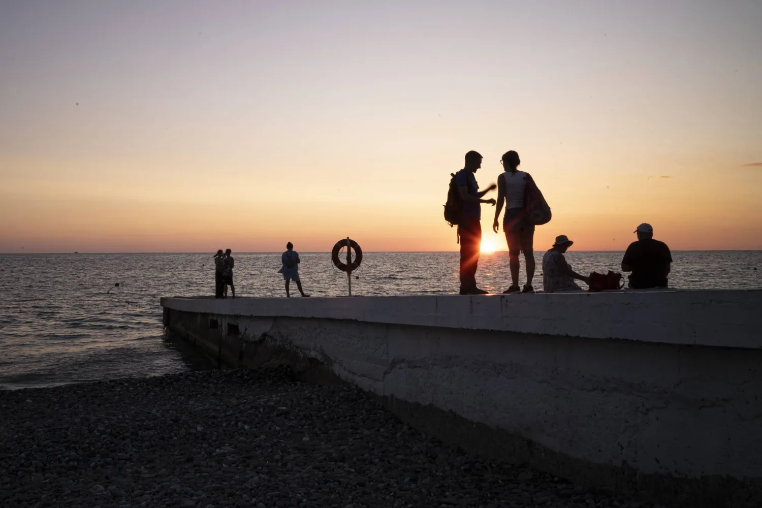 أشخاص يشاهدون غروب الشمس على رصيف بحري في سوتشي (أ.ب)