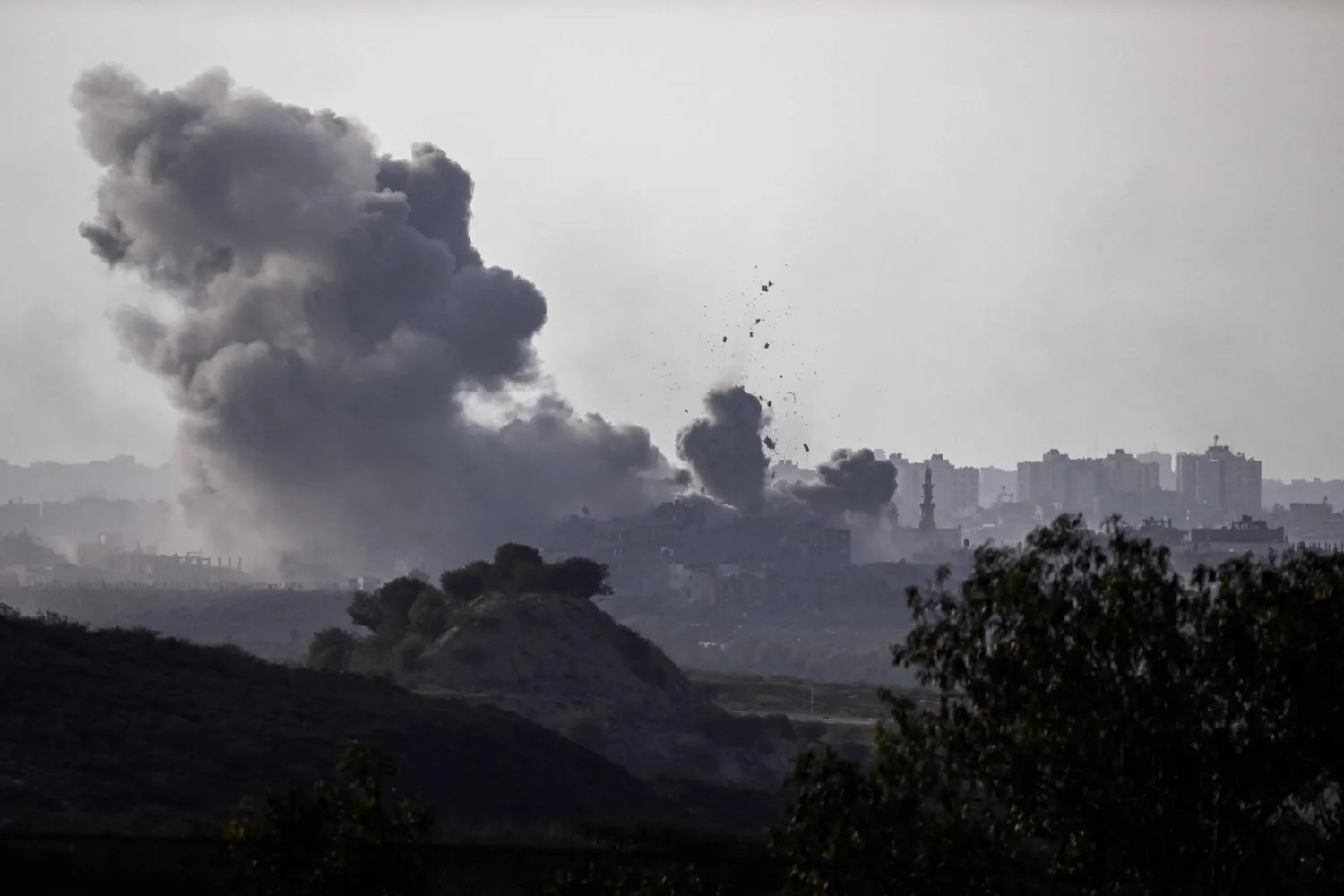 A picture taken from Sderot shows smoke plumes rising above buildings during an Israeli strike on the northern Gaza Strip on October 14, 2023. (Photo by Aris MESSINIS / AFP)